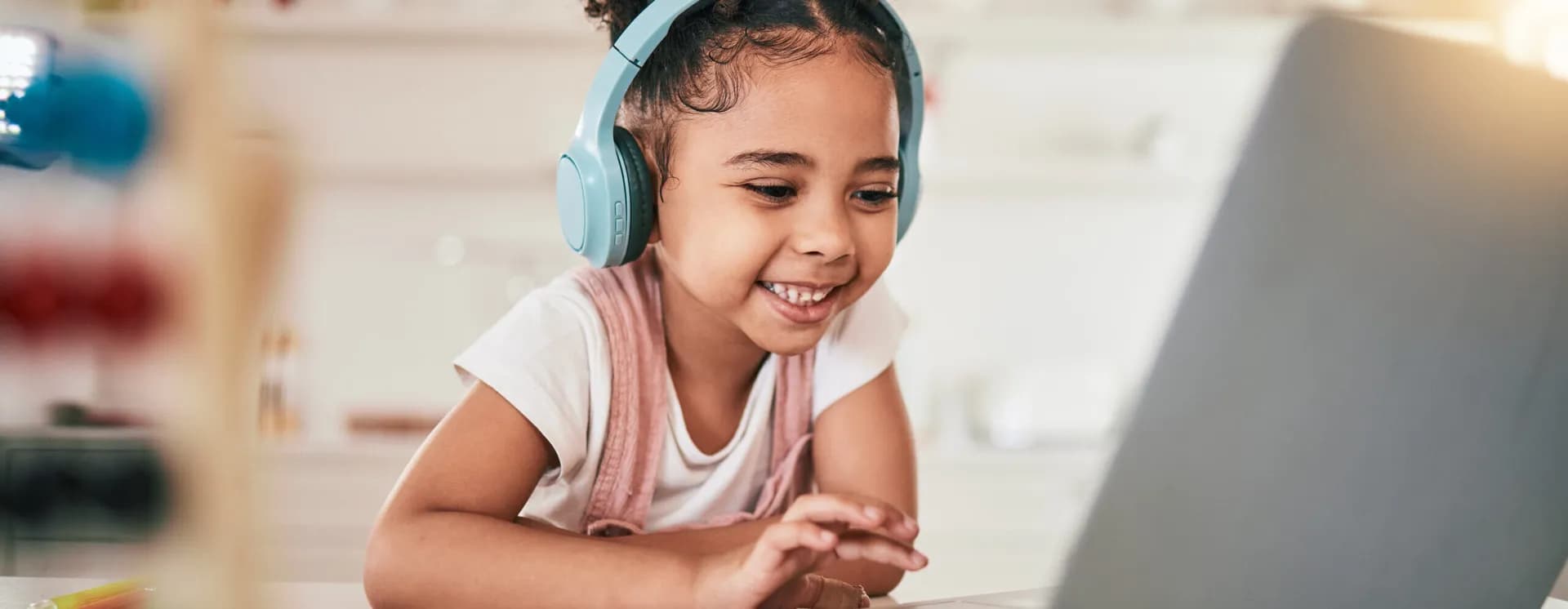 Smiling girl with headphones learning on a laptop at home
